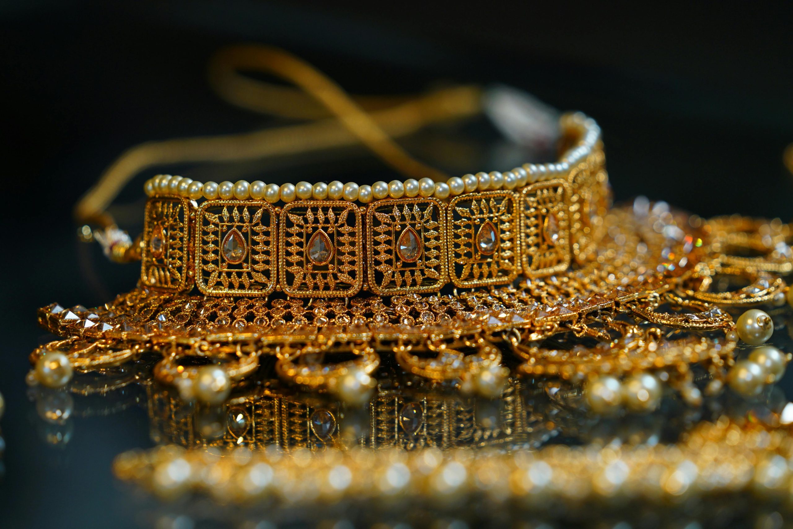 Stylish golden bracelet or necklace in oriental style decorated with pearls and crystals placed on black surface